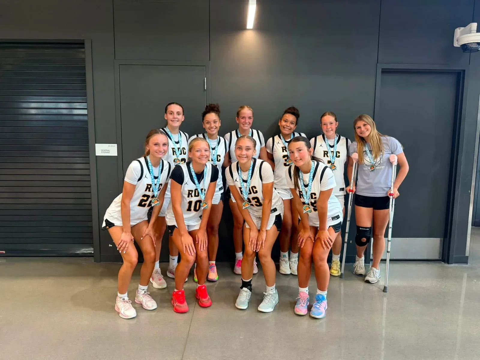 RDC basketball teammates in white uniforms wearing medals