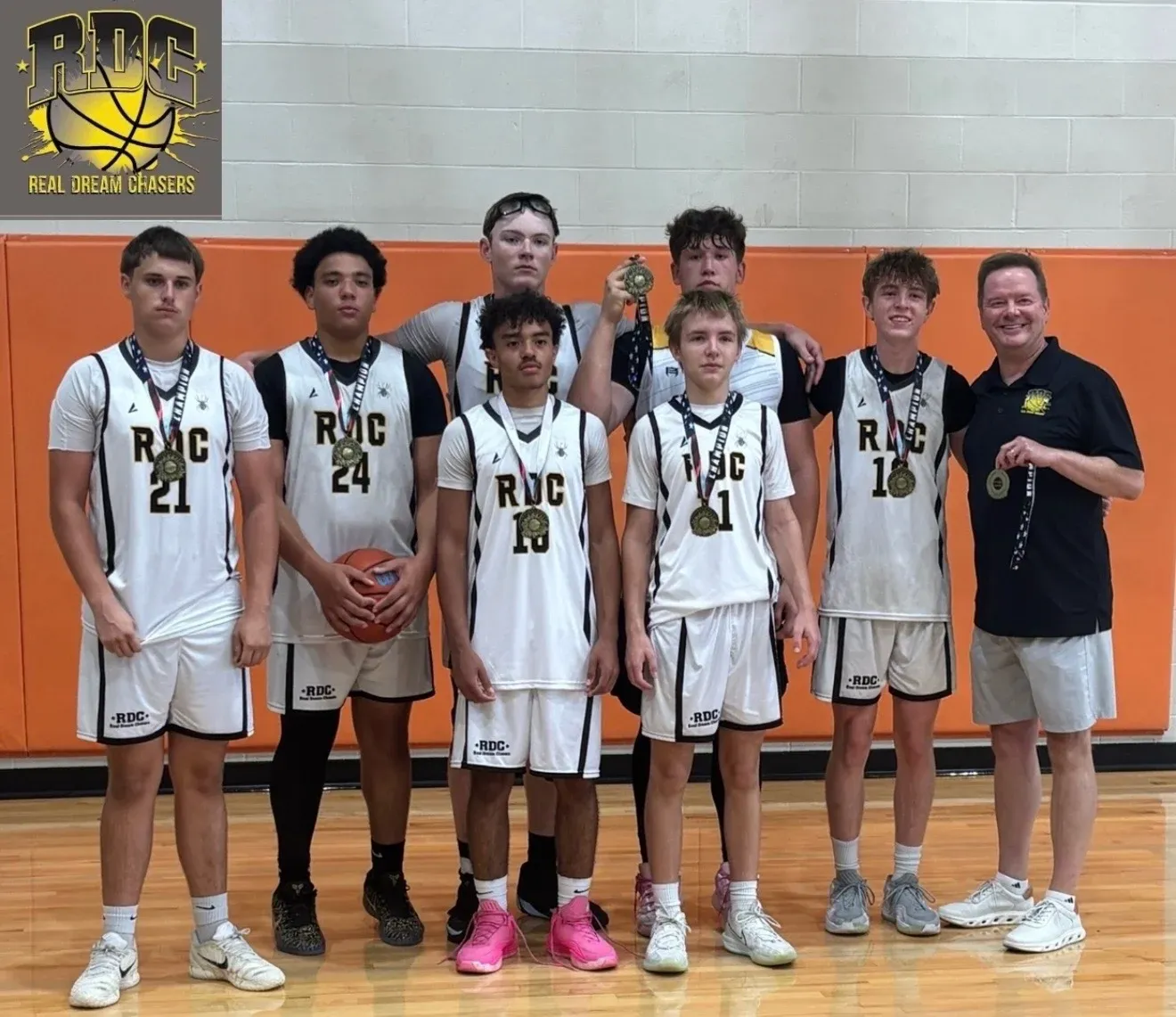 RDC basketball players in white uniforms with their coach and medals