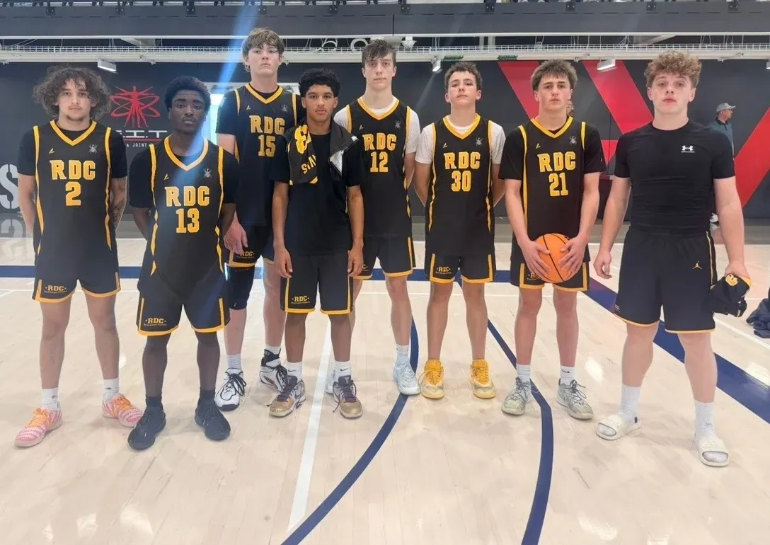 RDC basketball team in black and gold uniforms on a court
